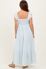 woman wearing a light blue tiered maxi dress with short sleeves and a smocked bodice, shown from the back