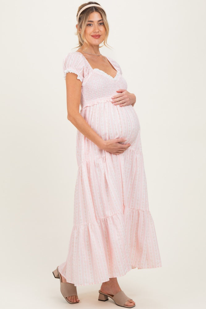 woman wearing a pink maternity maxi dress with puff sleeves and holding her baby bump