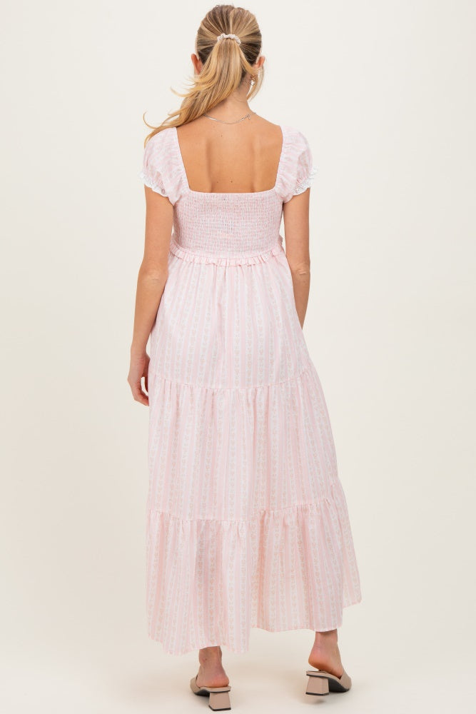 woman wearing a pink and white tiered maternity maxi dress, showing a smocked bodice and short puff sleeves