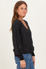 woman wearing a black polka dot long sleeve blouse with a v-neckline and puffed sleeves