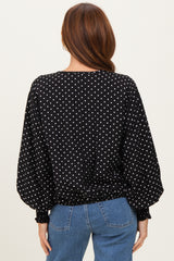 woman wearing a black polka dot blouse with puffed sleeves and a cinched waist, seen from the back