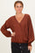 woman wearing a rust brown polka dot wrap top with balloon sleeves and a v-neckline, paired with a black skirt