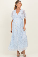 woman wearing a light blue floral print maxi maternity dress with short flutter sleeves and button details, showing her baby bump