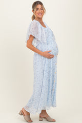 woman wearing a light blue floral maternity dress with a flowing cape sleeve and a visible baby bump