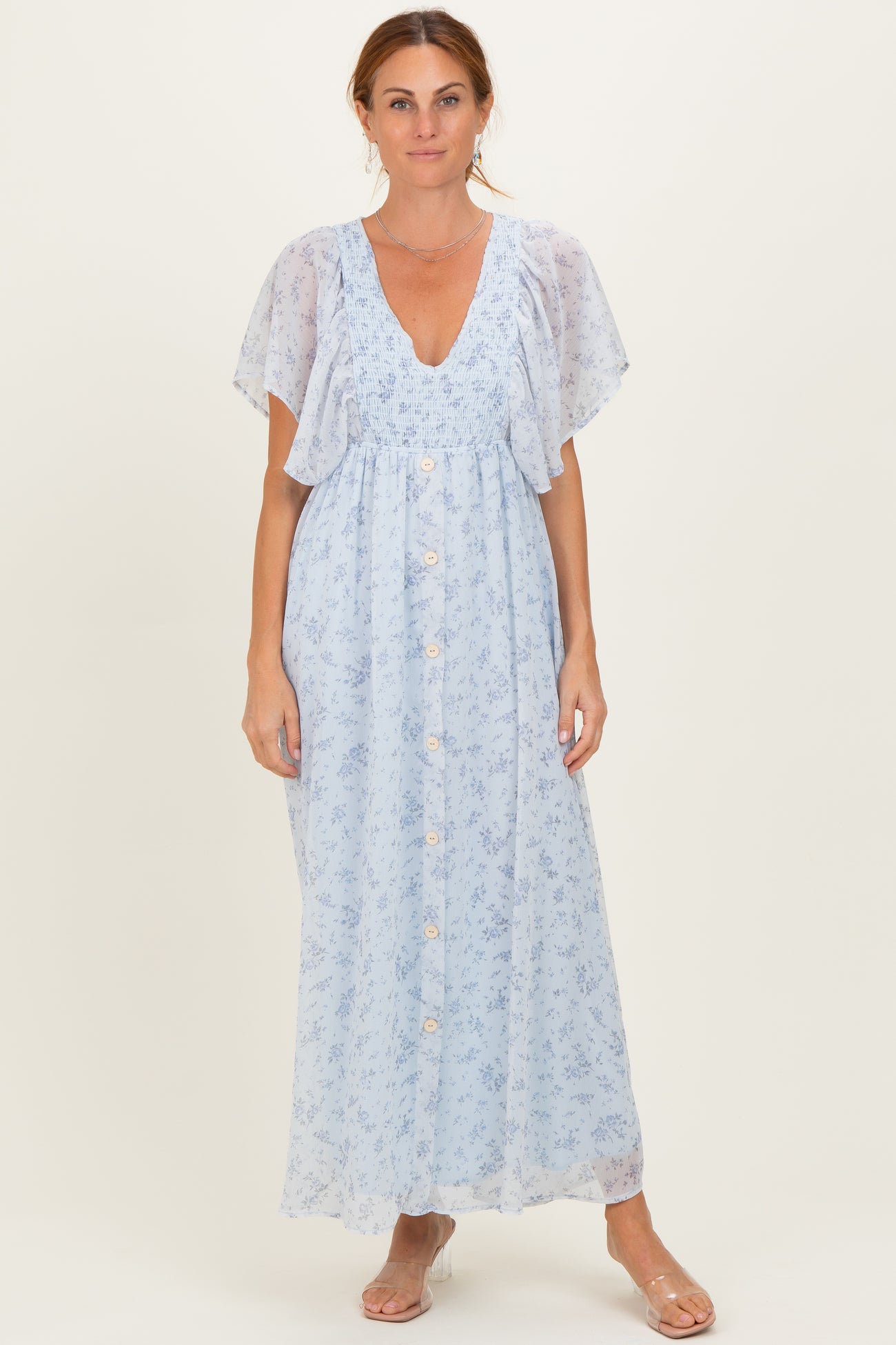 woman wearing a light blue floral maxi dress with flutter sleeves and button details