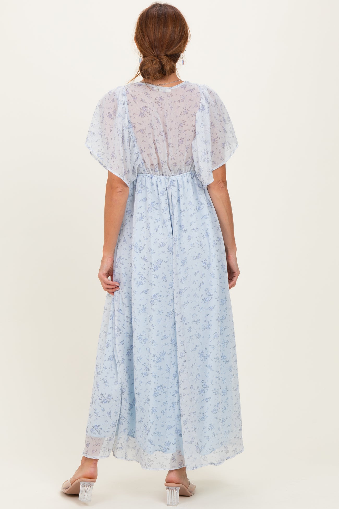 woman wearing a light blue floral maxi dress with short flutter sleeves, viewed from the back