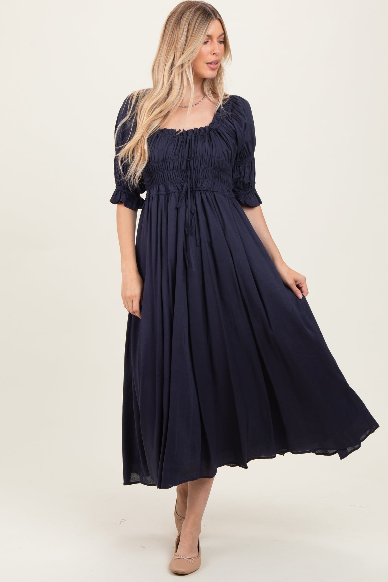 woman wearing a navy blue smocked maxi dress with puff sleeves and a drawstring waist