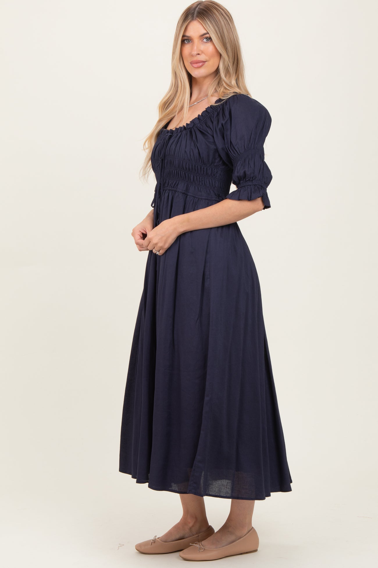 woman wearing a navy blue long sleeve midi dress with puff sleeves and shirred bodice