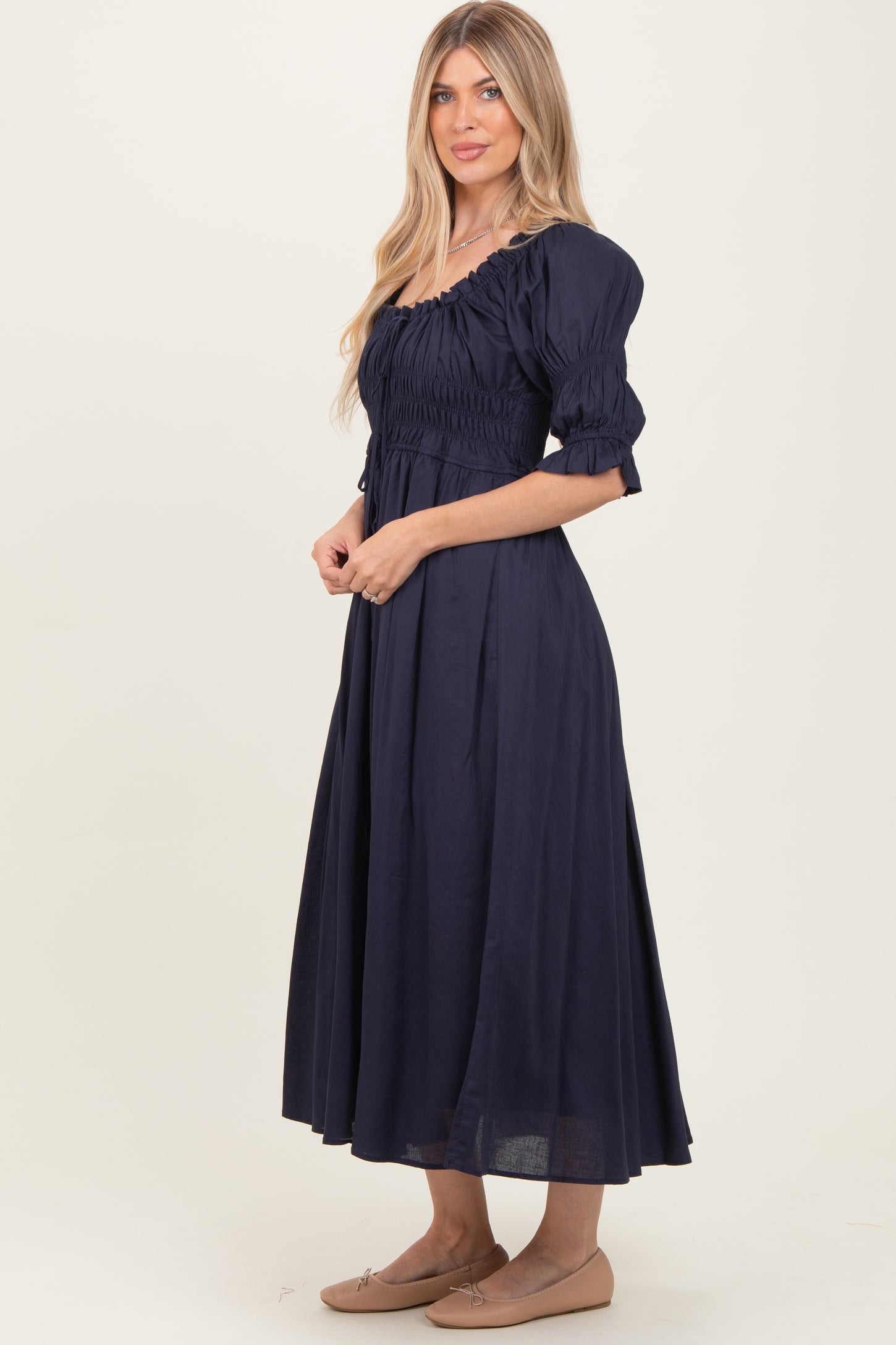 woman wearing a navy blue long sleeve midi dress with puff sleeves and shirred bodice