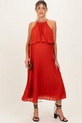woman wearing a flowy red maternity dress with pleats and a halter neckline, showcasing her baby bump