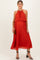 woman wearing a flowy red maternity dress with pleats and a halter neckline, showcasing her baby bump