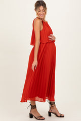 woman wearing a sleeveless red maternity dress with pleats and holding her baby bump