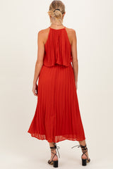 woman wearing a red pleated maternity dress with a halter neckline and back button details