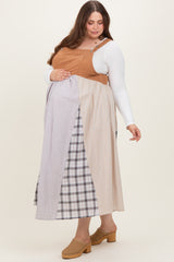 woman wearing a color-blocked maternity plus dress with a brown top and patterned skirt, holding her baby bump