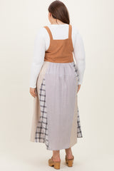 woman wearing a maternity plus tan corduroy overall dress with a long plaid skirt, viewed from the back