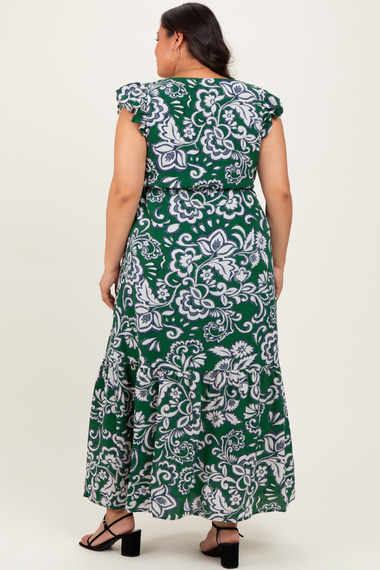 woman wearing a green floral print plus size maxi dress with ruffled sleeves and tiers, seen from the back