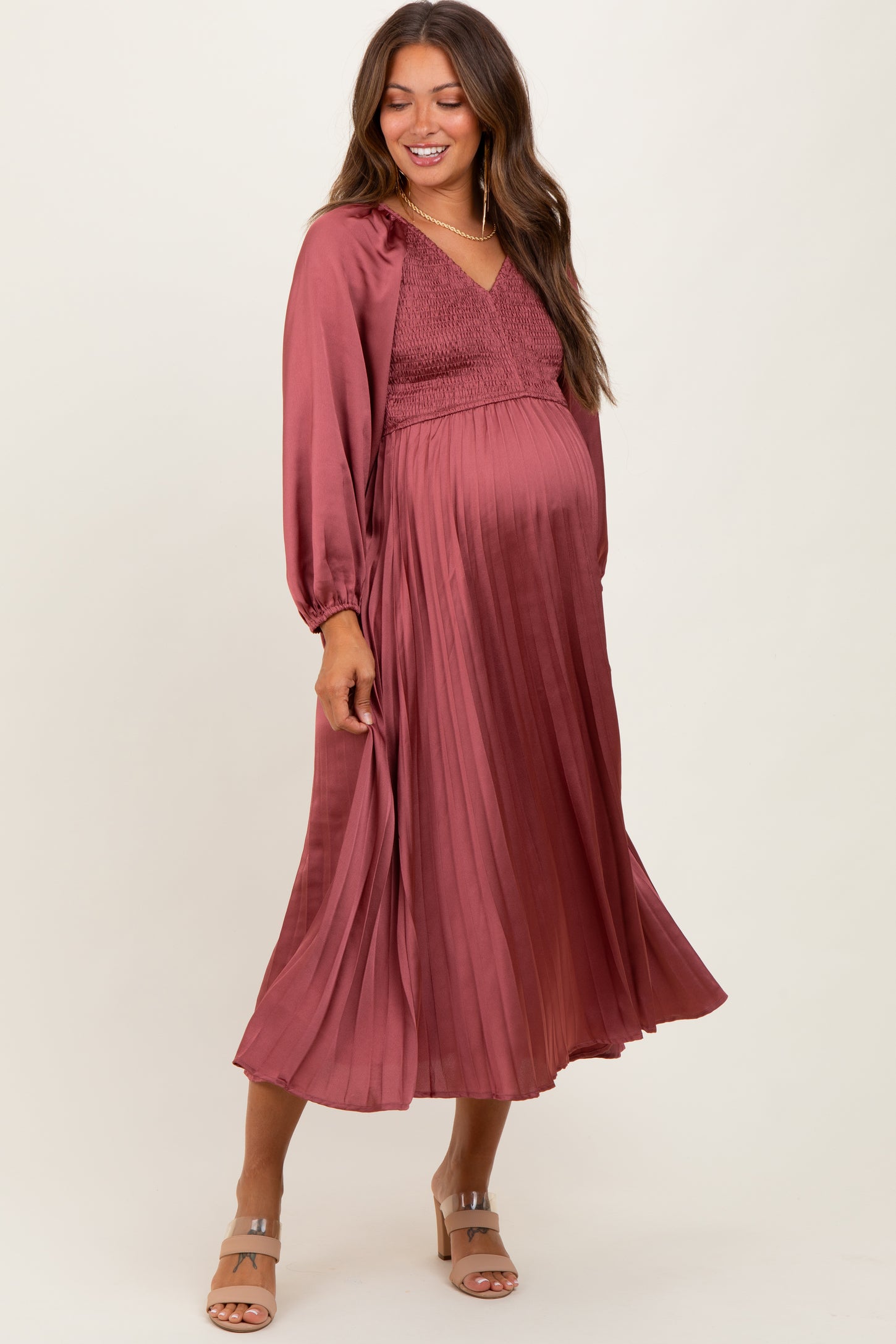 woman wearing a dusty rose maternity dress with a smocked bodice and flowing pleated skirt, showing baby bump