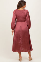 woman wearing a burgundy maternity dress with a smocked bodice and pleated skirt, shown from the back