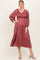 woman wearing a rust-colored pleated midi dress with smocked bodice and puff sleeves