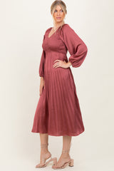 woman wearing a dusty rose pleated midi dress with long puff sleeves and a smocked bodice, styled with strappy heels