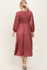 woman wearing a wine-colored midi dress with smocked bodice and long sleeves, shown from the back