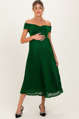 woman wearing a dark green pleated off-shoulder maternity dress with a visible baby bump