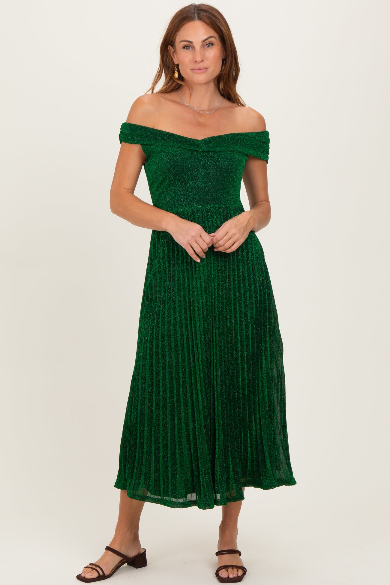 woman wearing a green off-the-shoulder pleated dress with a fitted bodice and a flowy skirt