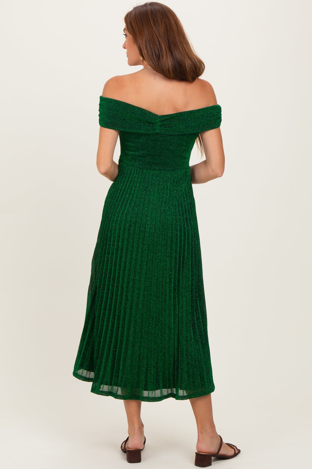 woman wearing a green off-the-shoulder pleated midi dress with a fitted bodice and flared skirt