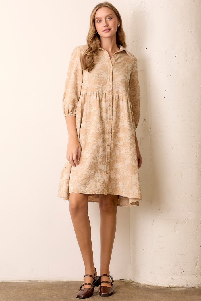woman wearing a beige floral button-up dress with three-quarter sleeves and an asymmetrical hemline