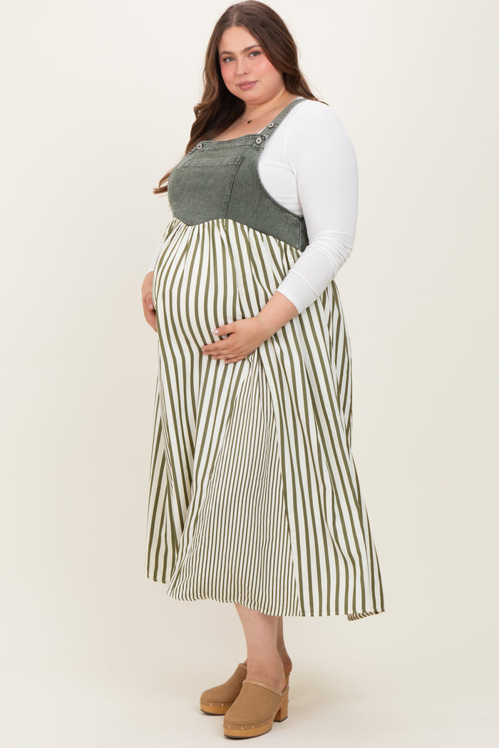 woman wearing a green and white striped maternity dress with overalls, holding her baby bump