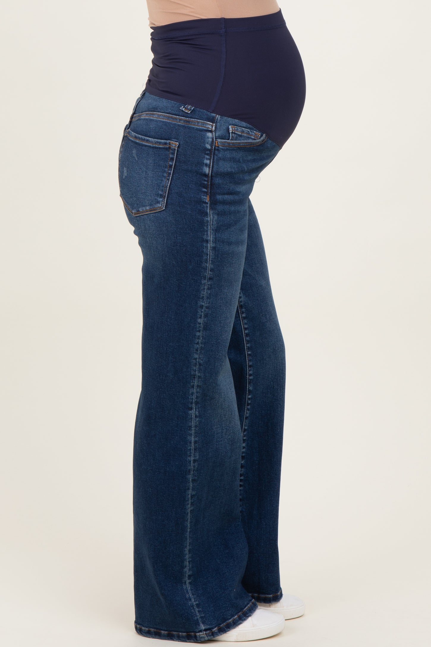 woman wearing dark wash maternity flared jeans with a navy belly panel covering her baby bump