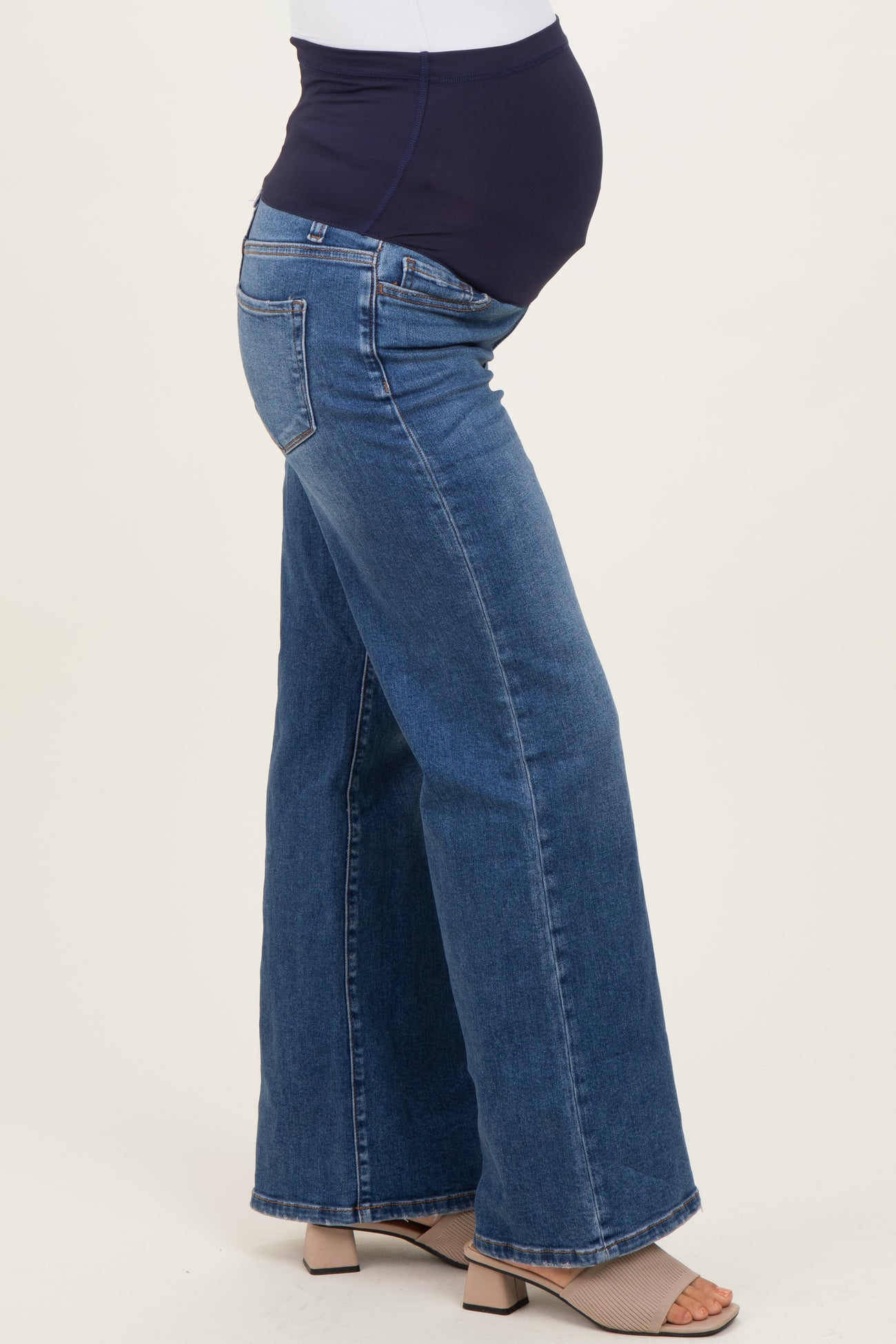 woman wearing dark wash flared maternity jeans with a supportive belly band and a visible baby bump