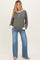woman wearing a green striped maternity top with white cuffs and blue flared maternity jeans