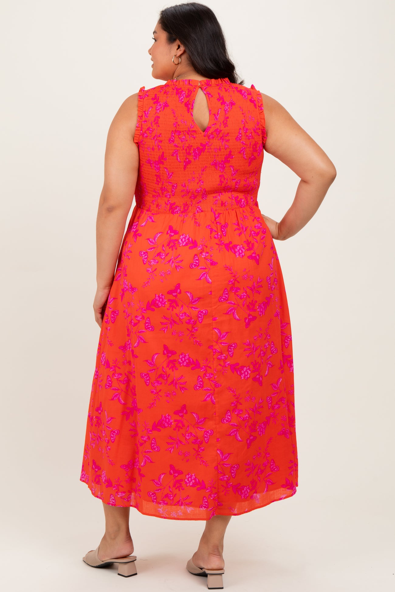 woman wearing a vibrant orange floral maxi dress with a smocked bodice and a keyhole back detail