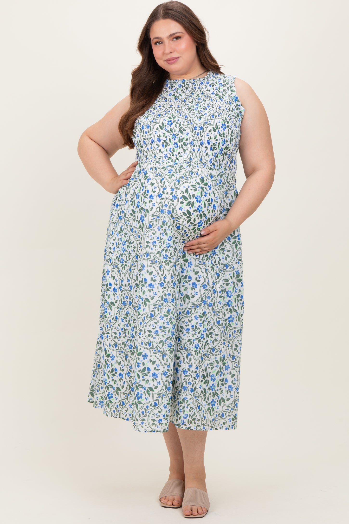 woman wearing a light blue floral sleeveless maternity dress and holding her baby bump