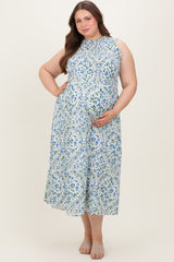 woman wearing a light blue floral sleeveless maternity dress and holding her baby bump
