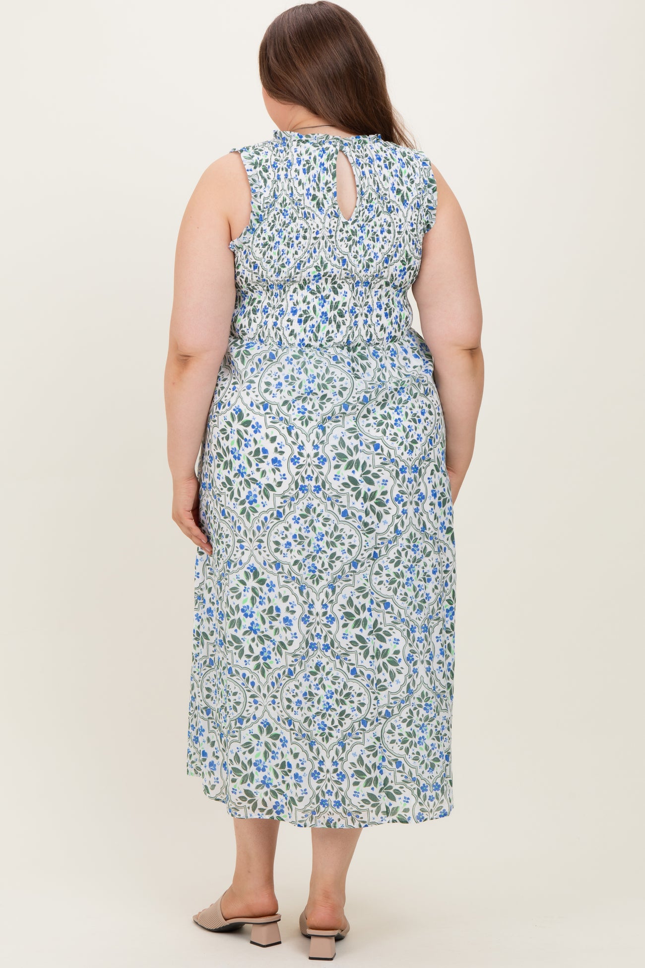 woman wearing a floral patterned maternity plus dress with a keyhole back detail and flowing skirt