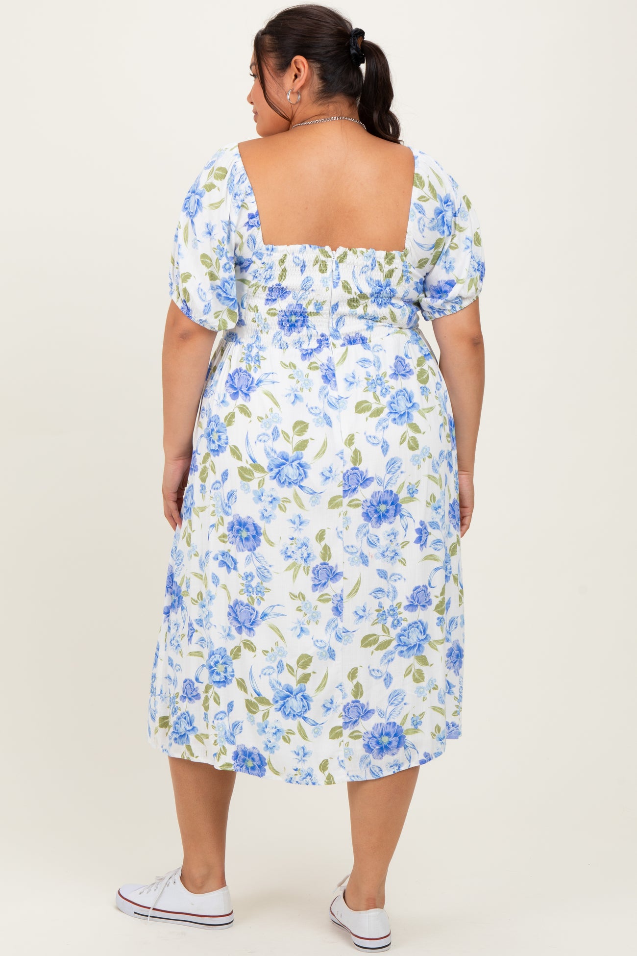 woman wearing a floral plus-size midi dress with puff sleeves and a square back detail