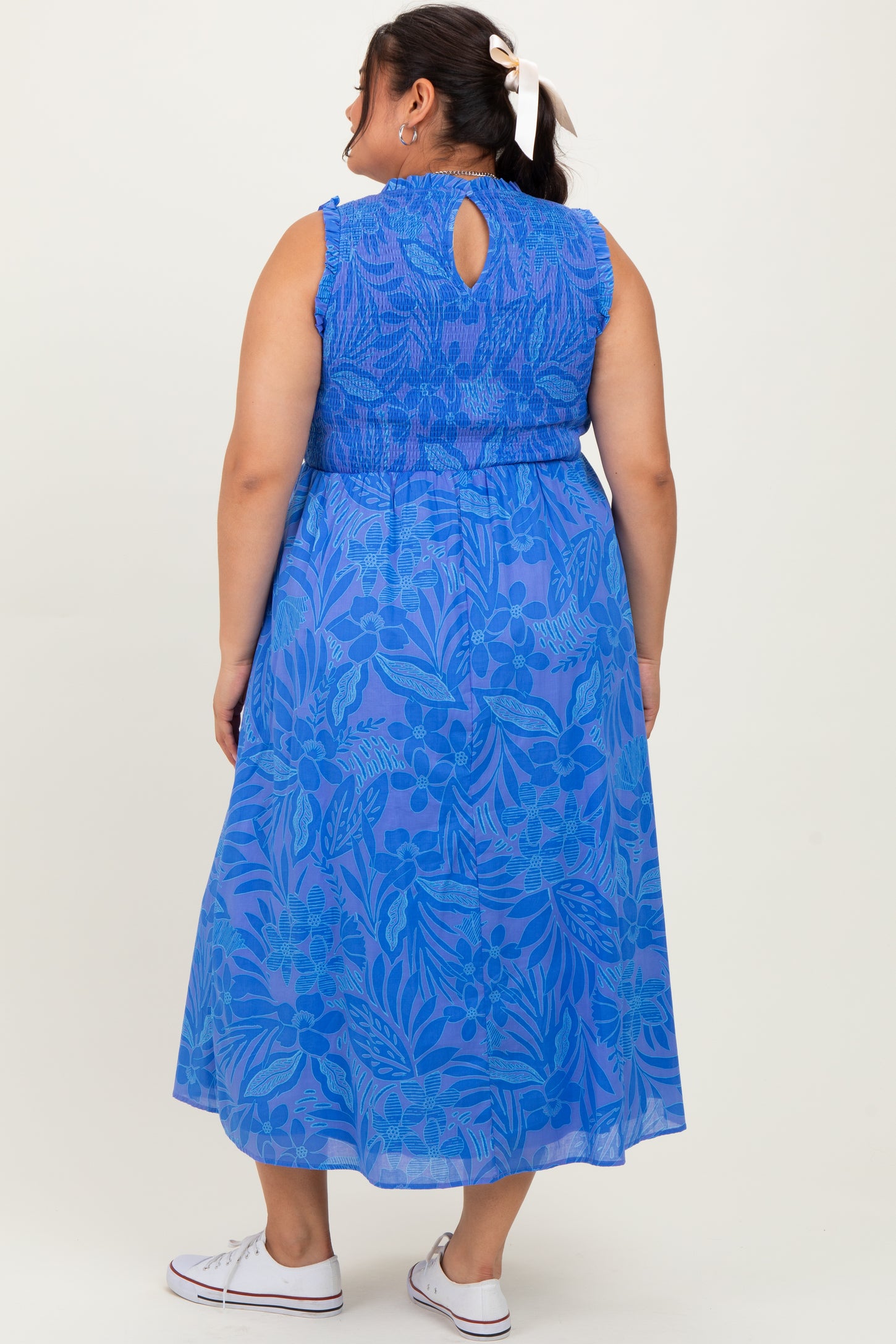woman wearing a blue floral maxi dress with a keyhole back and smocked bodice, seen from the back