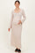woman wearing a beige long sleeve maternity dress with a square neckline and holding her baby bump