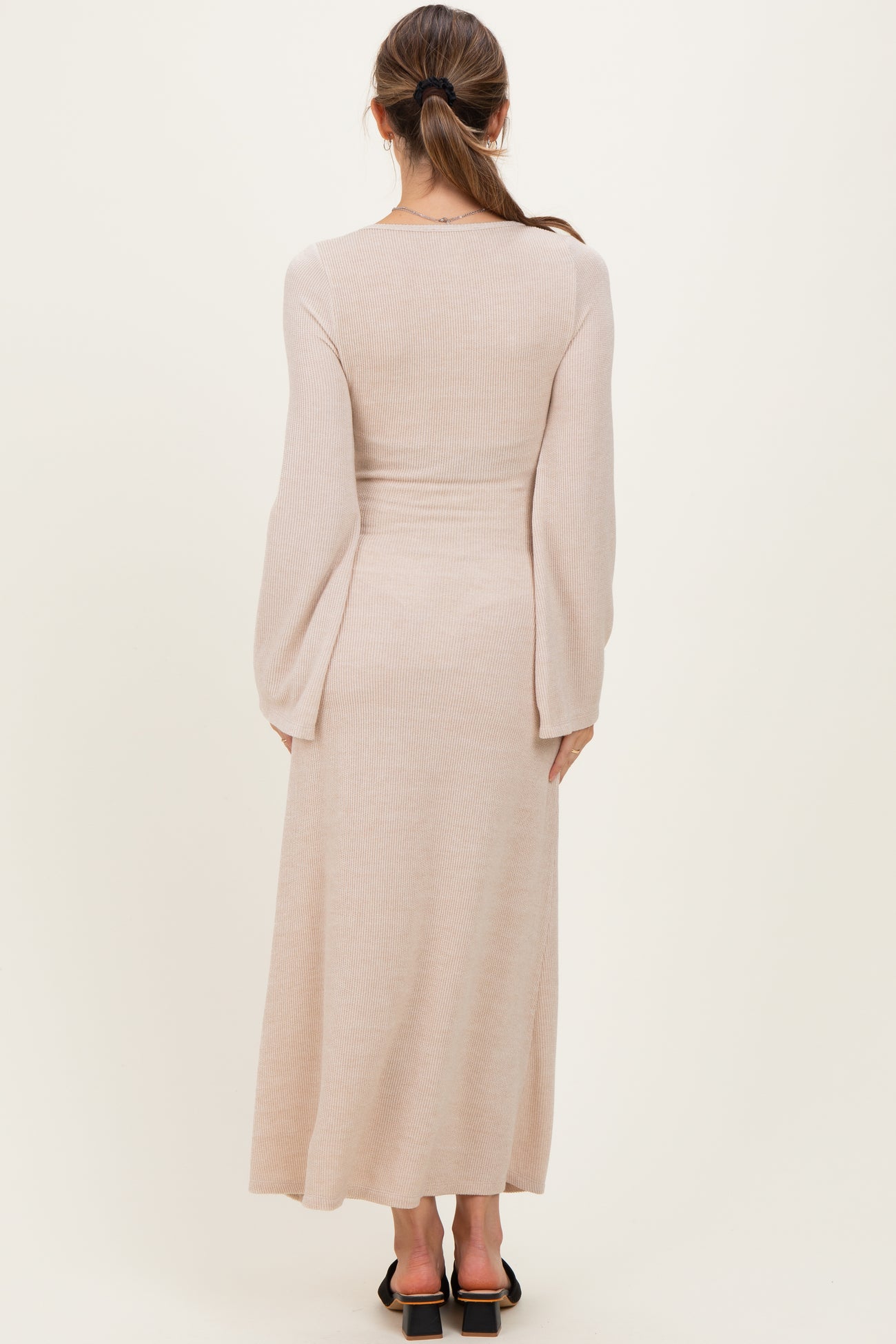 woman wearing a light beige long sleeve maternity maxi dress from the back