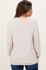 woman wearing a light beige maternity sweater with long sleeves, shown from the back