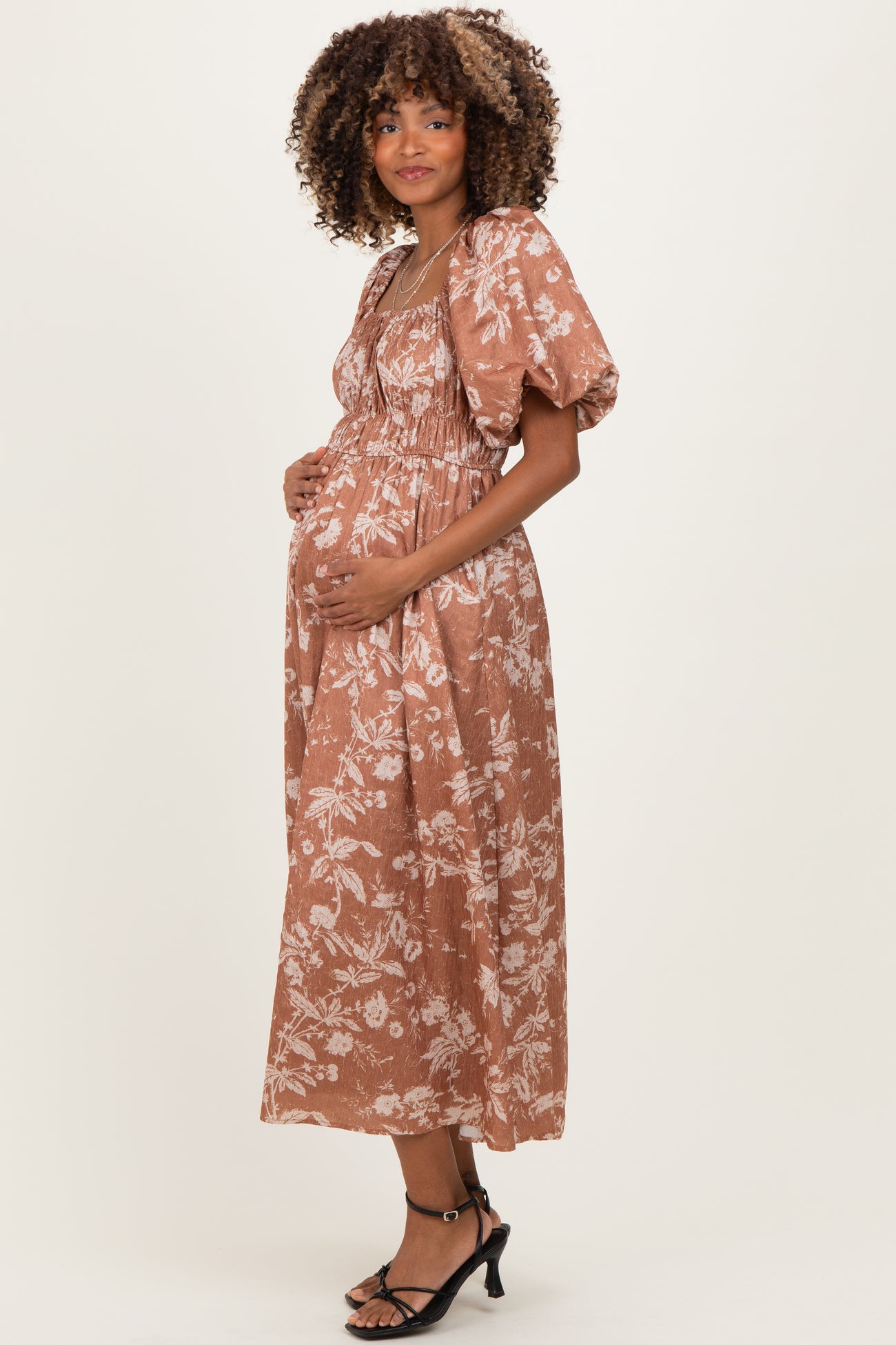 woman wearing a brown floral maternity dress with puff sleeves and a baby bump visible