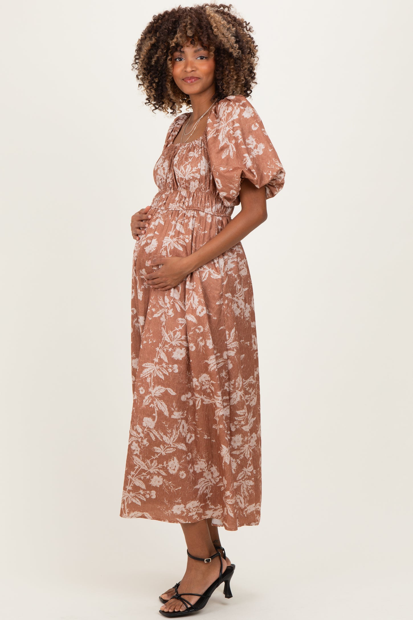 woman wearing a brown floral maternity dress with puff sleeves and a baby bump visible