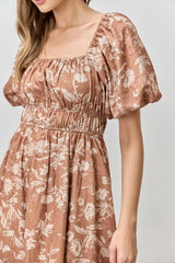 woman wearing a rust floral puff sleeve dress with a square neckline and smocked waist