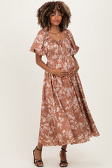 woman wearing a brown floral maternity maxi dress and holding her baby bump