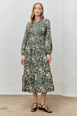 woman wearing a green floral midi dress with long sleeves and a tiered skirt, styled with brown shoes