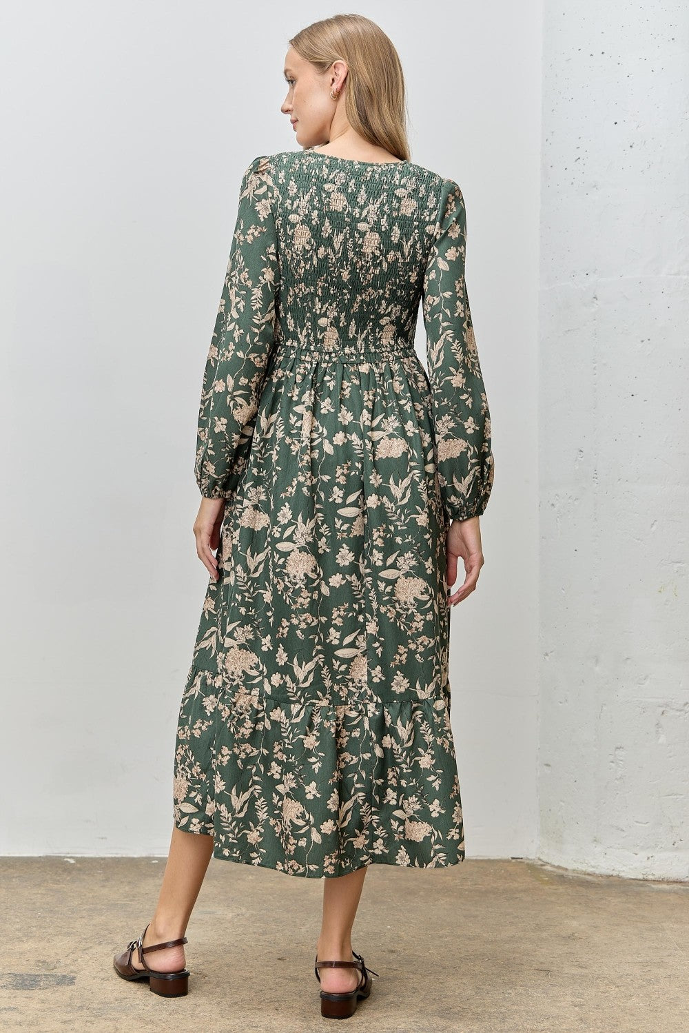 woman wearing a green floral long sleeve maxi dress with a smocked back and tiered skirt, seen from the back