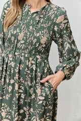 woman wearing a green floral long sleeve dress with smocked bodice and pockets