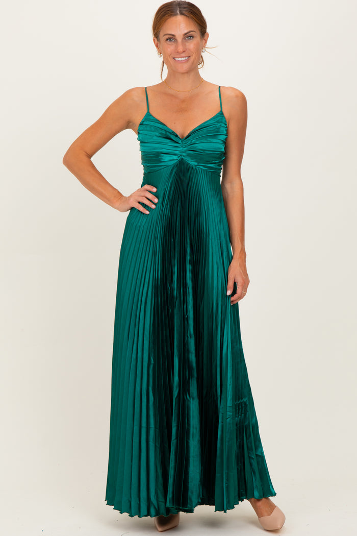 woman wearing a long emerald green pleated dress with spaghetti straps and a fitted bodice